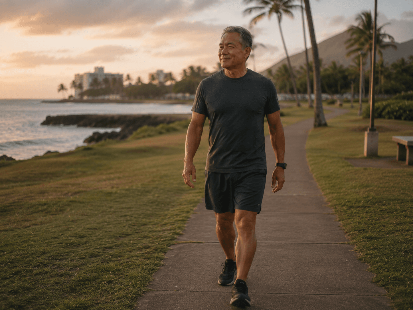 A man walking confidently along an oceanside path at sunset, palm trees and mountains in the background